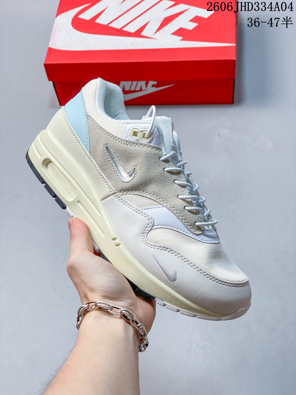 Nike Air Max 1 sneaker in light blue and white with blue Swoosh detailing.