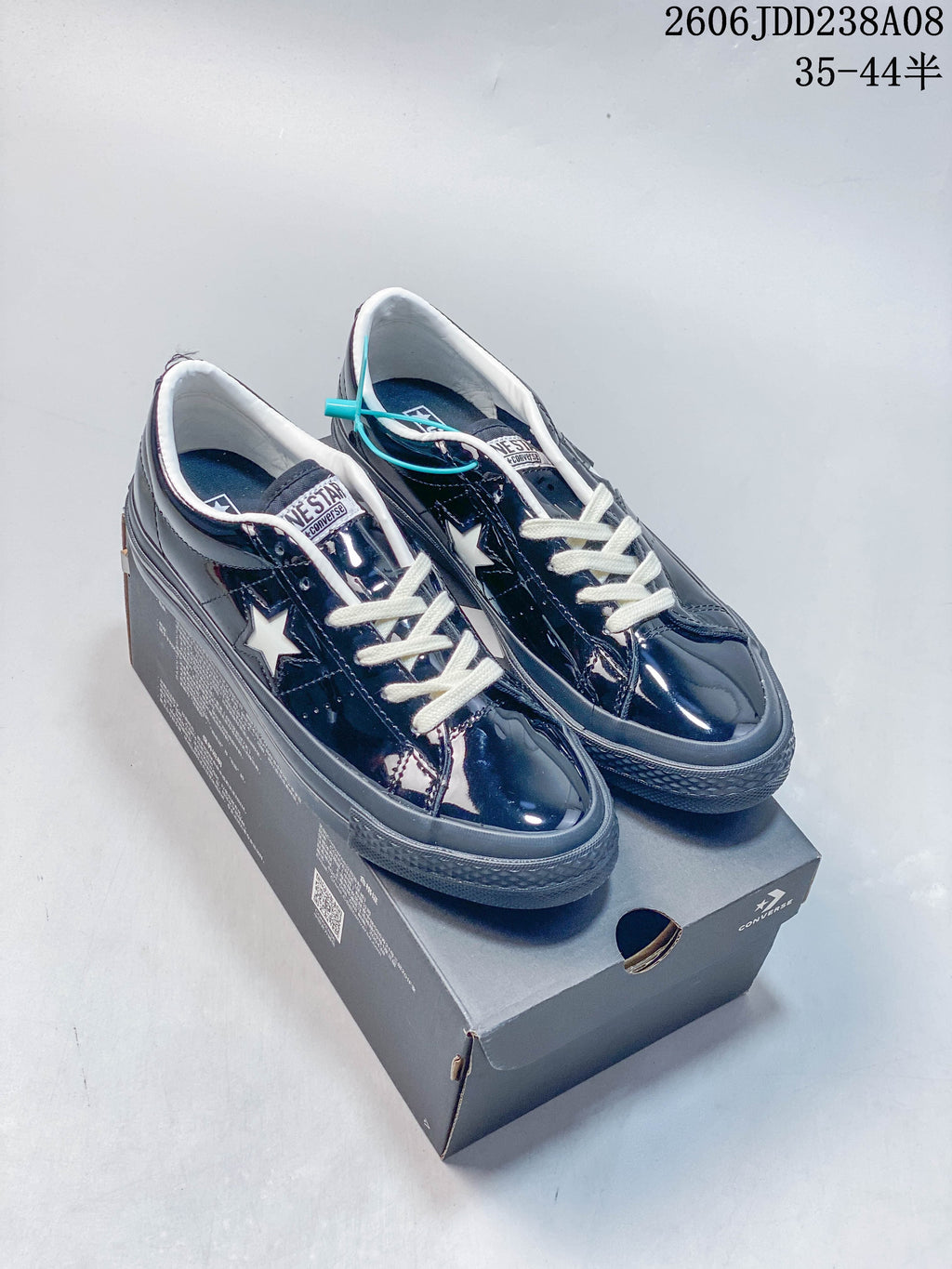 Pair of glossy navy Converse One Star low-top sneakers with cream laces displayed on a shoe box