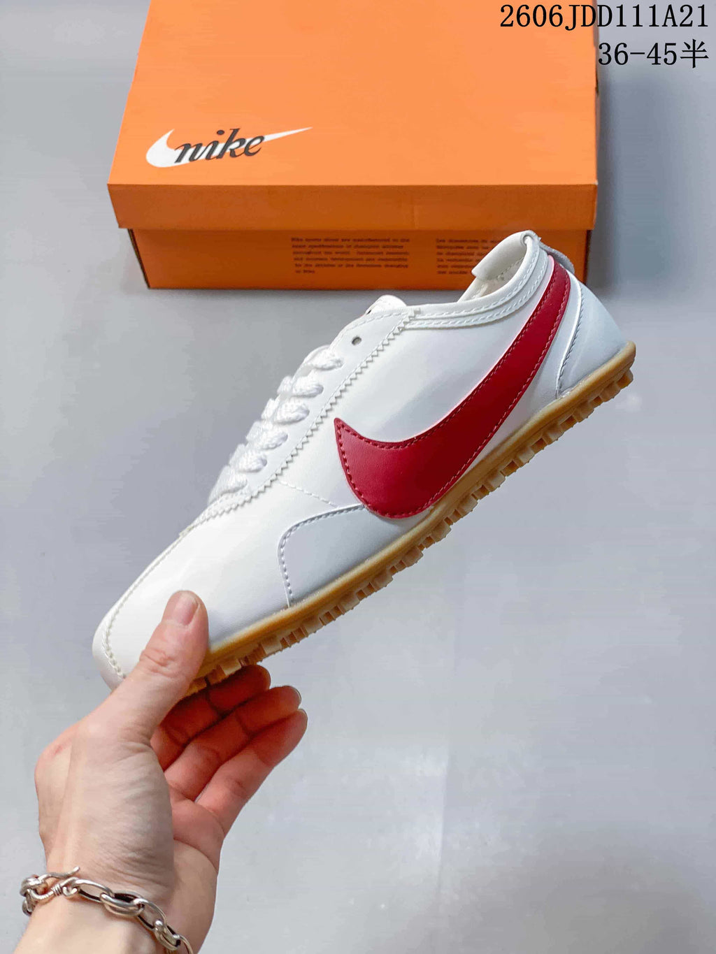 Side profile of a white low-top sneaker with a red side accent and gum-colored outsole