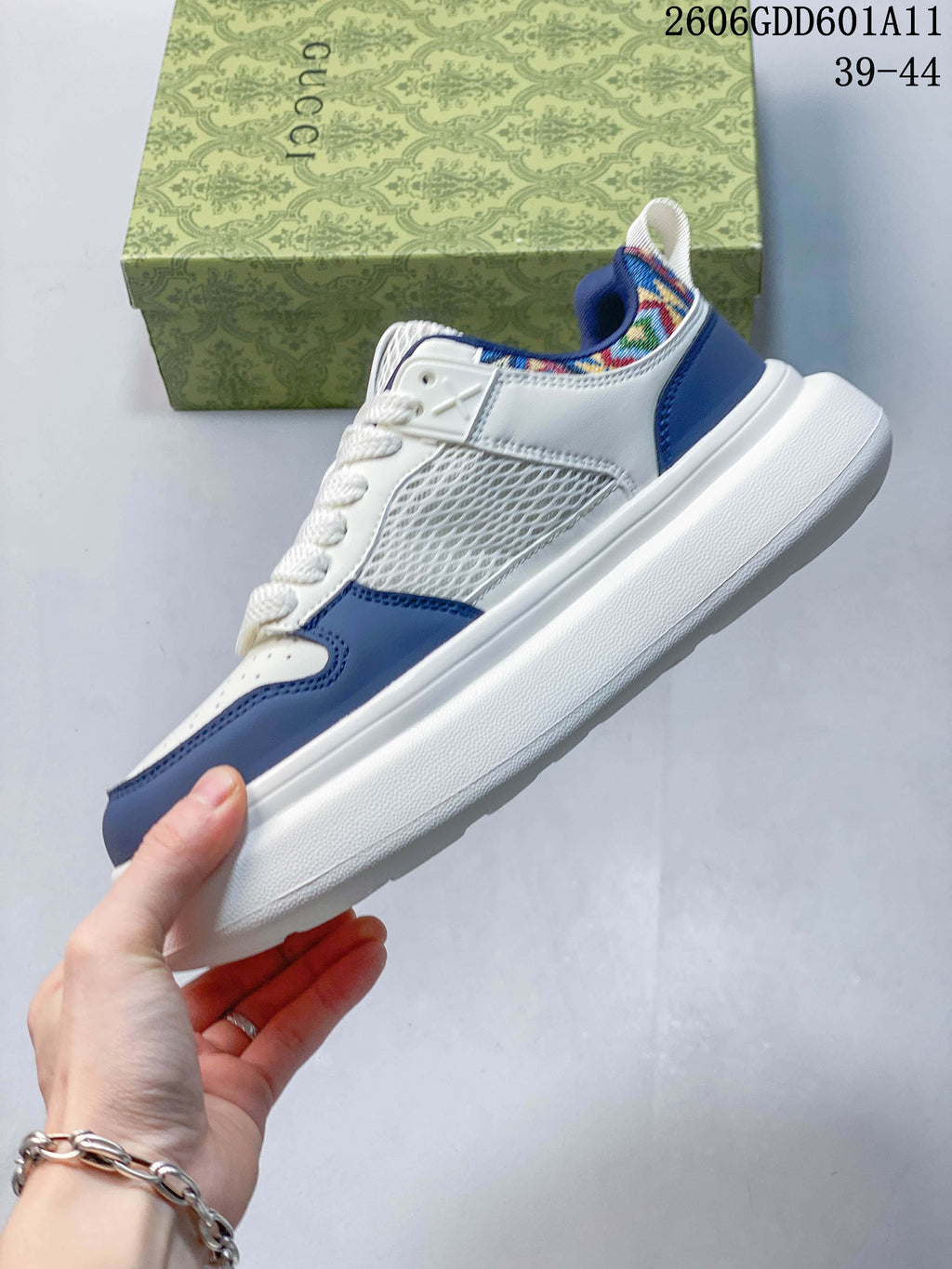 Side view of the white and blue sneakers with mesh inserts and a thick white sole.