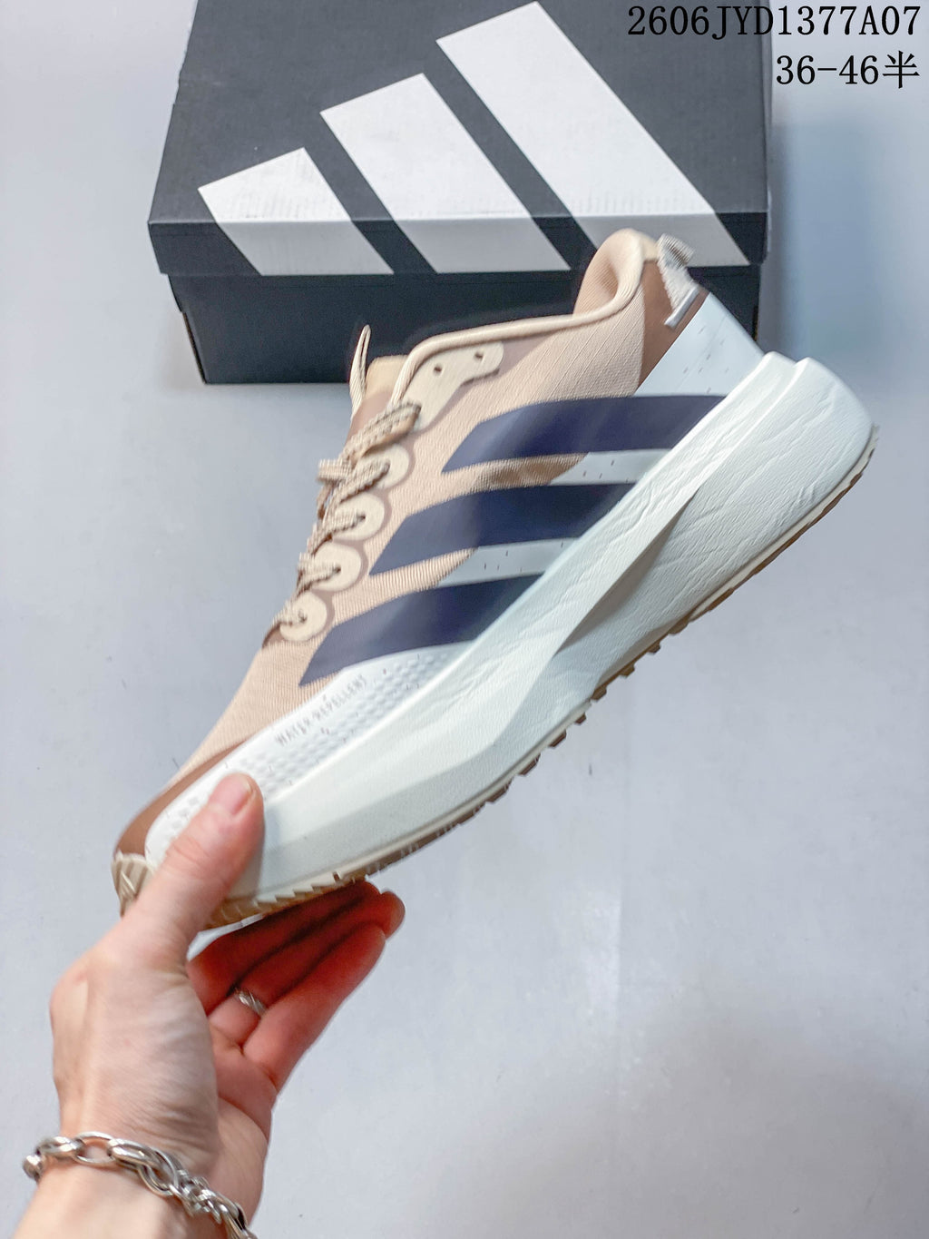 Side view of a beige Adidas Adizero Evo SL running shoe with navy stripes and a white midsole.