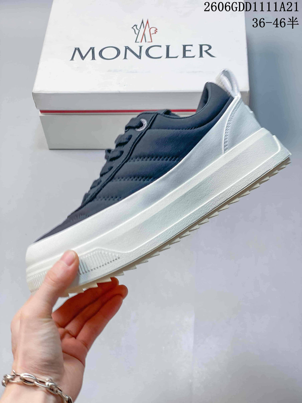 Side view of a navy Moncler sneaker with a contrasting white sole