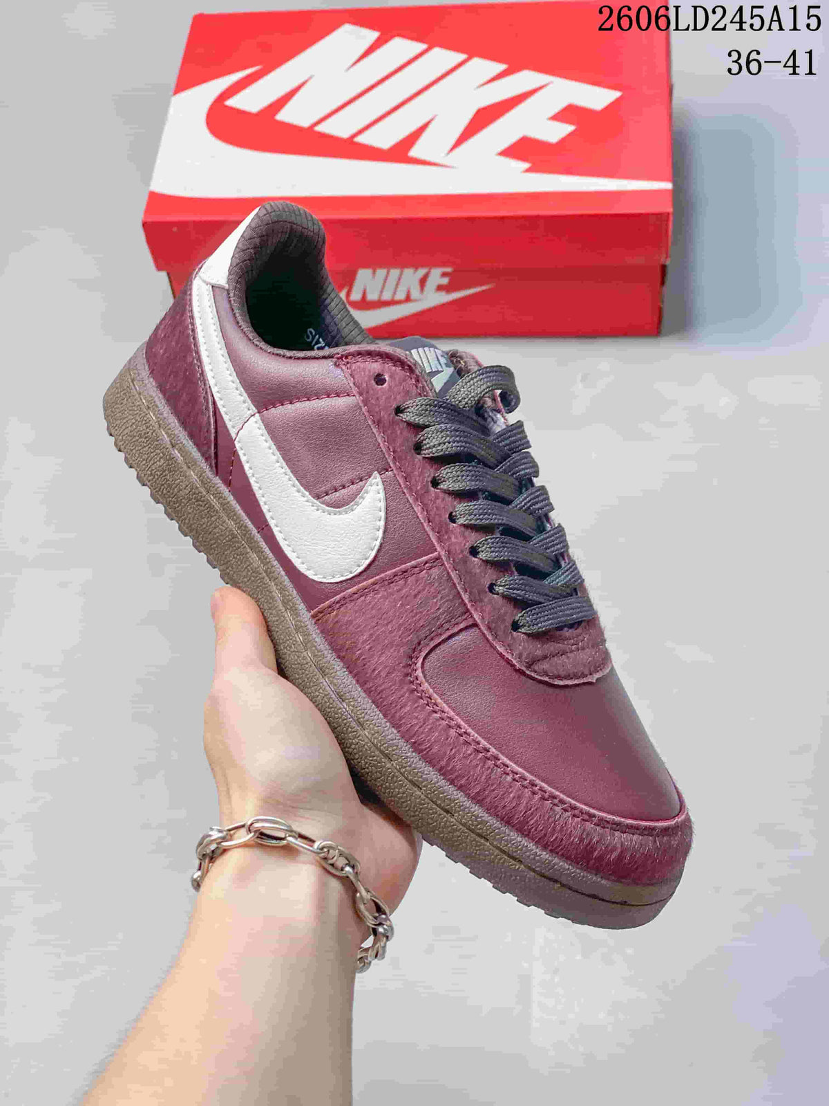 Angled side view of the burgundy sneaker with a light-colored side panel and dark laces.