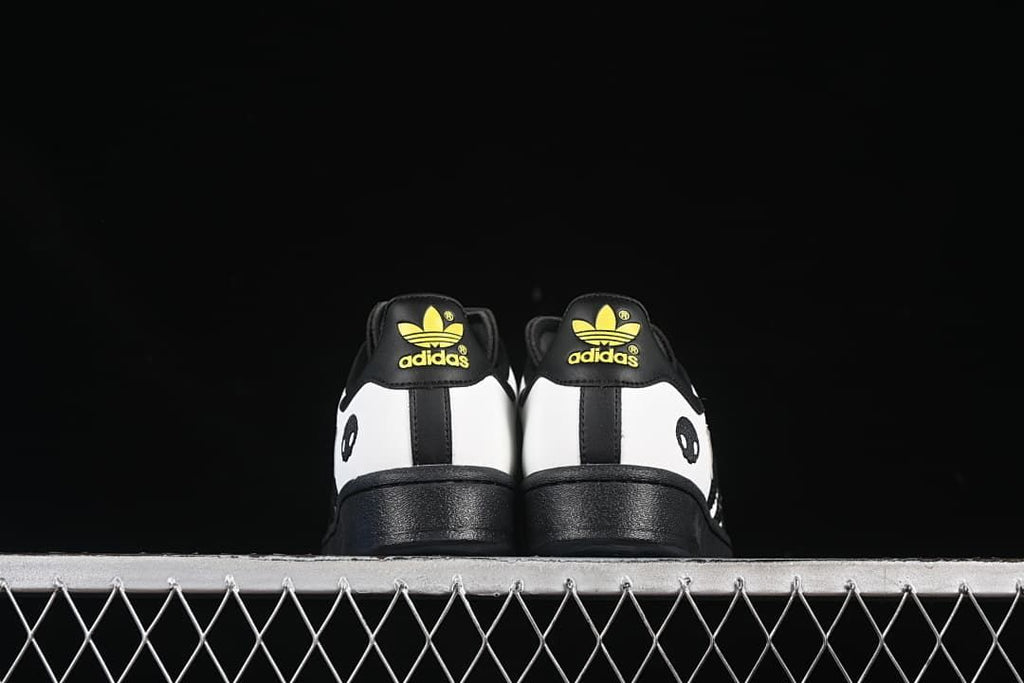 Rear view of both shoes with black soles and yellow heel logos
