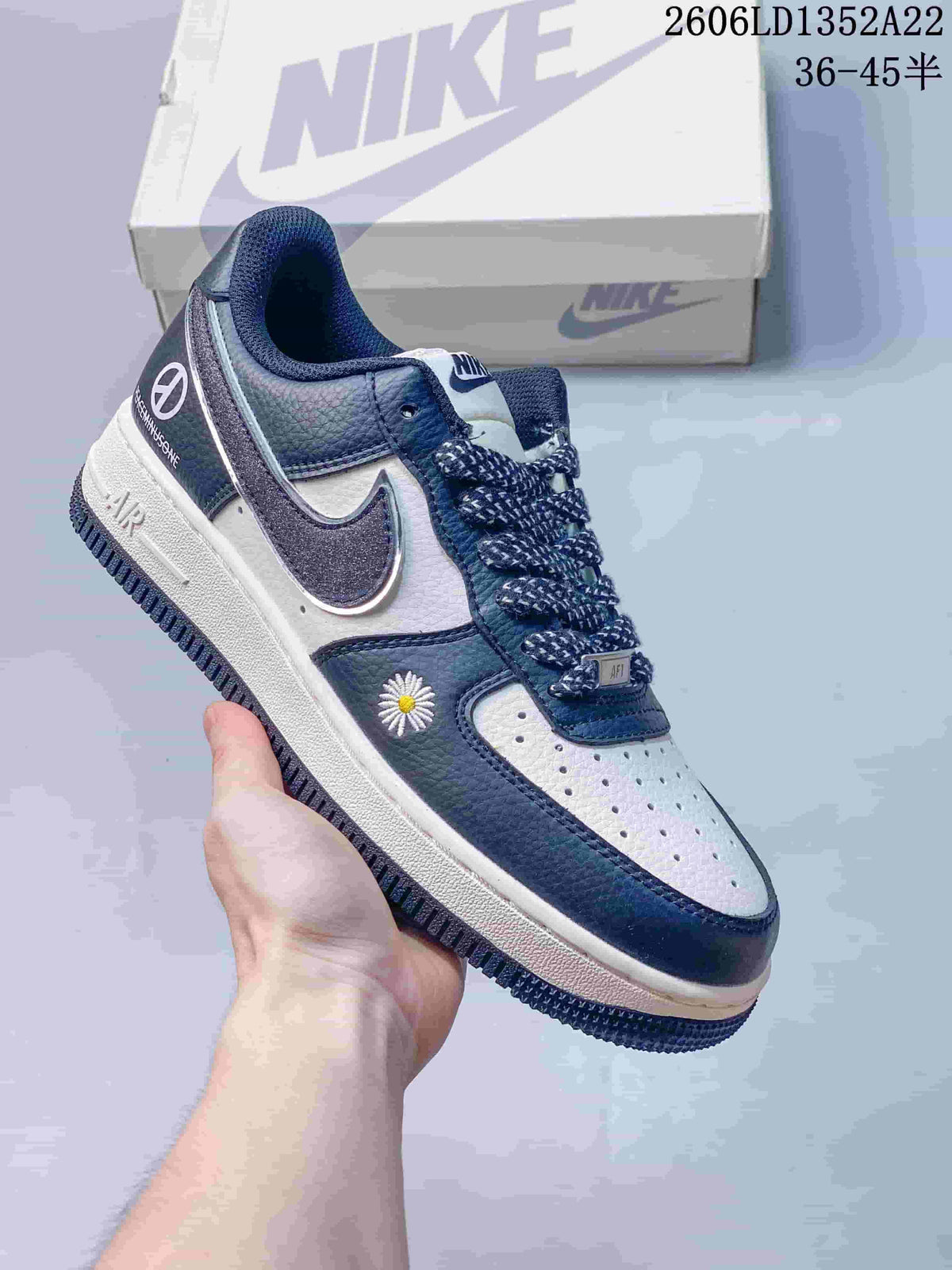 Navy and white low-top sneaker with patterned laces, glitter-effect Swoosh and daisy embroidery.