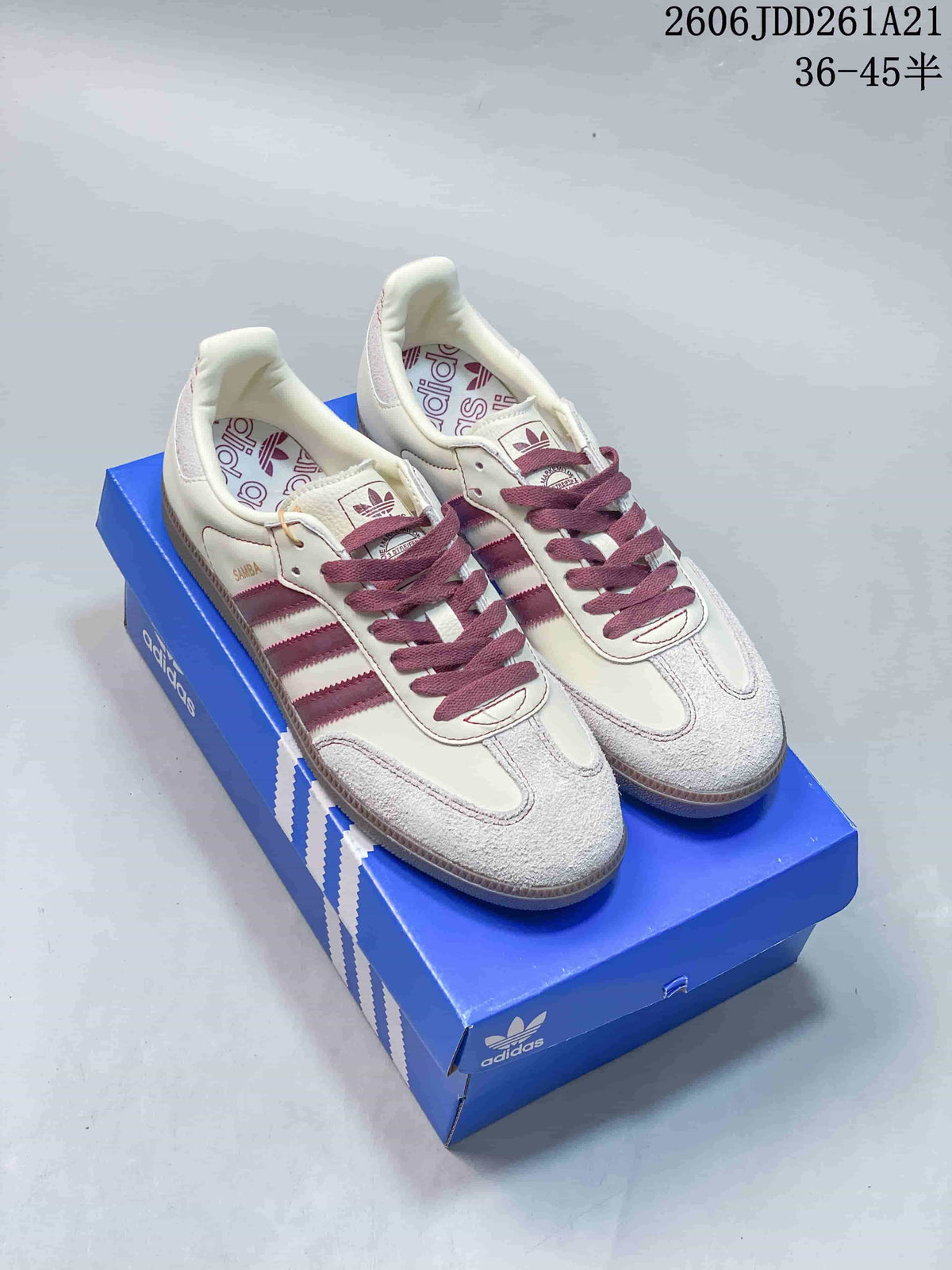 Cream adidas Samba low-top sneakers with burgundy stripes and burgundy laces on a blue shoebox.