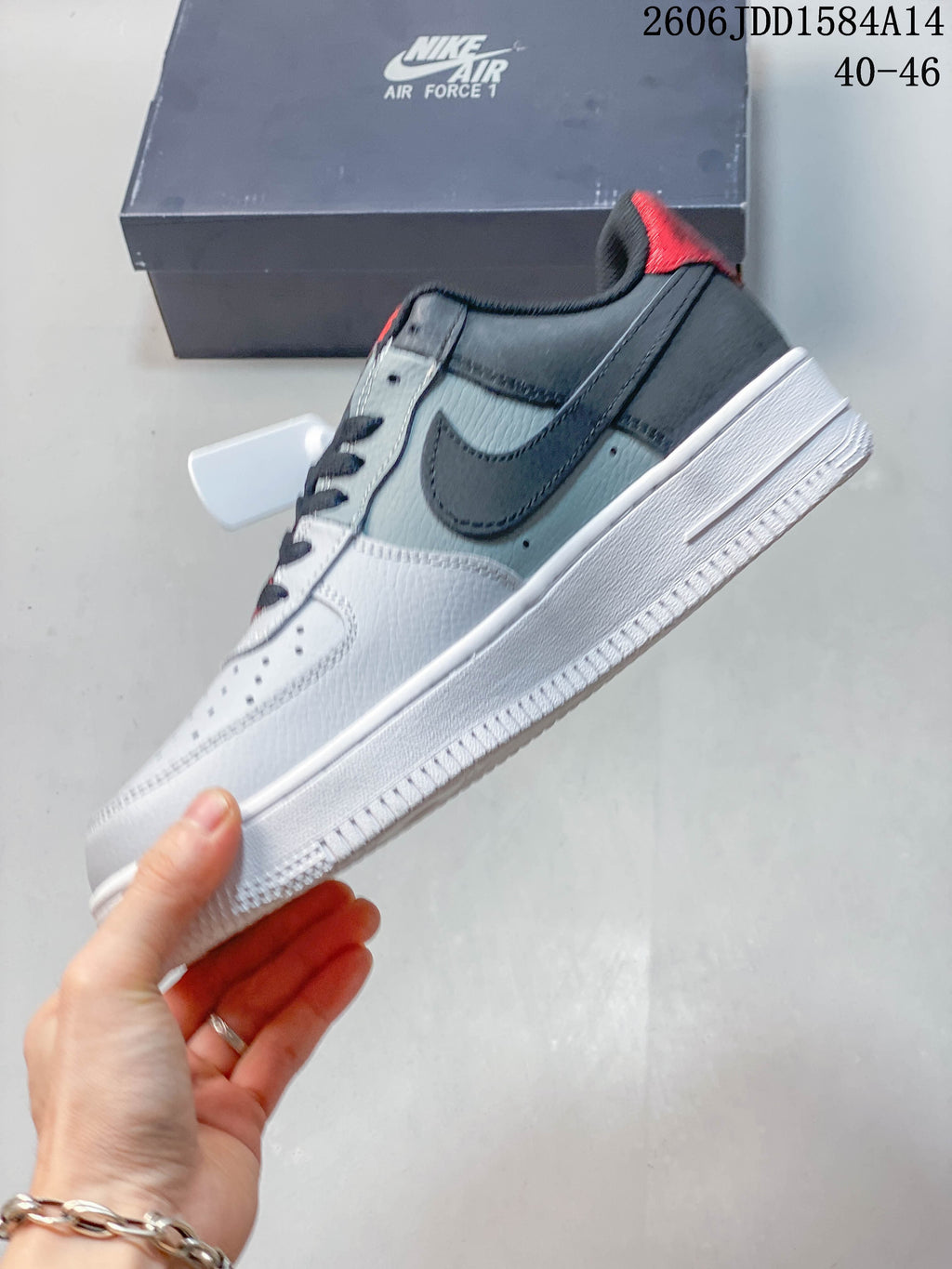 Side view of the white and grey low-top sneaker with a dark Swoosh and red heel accent
