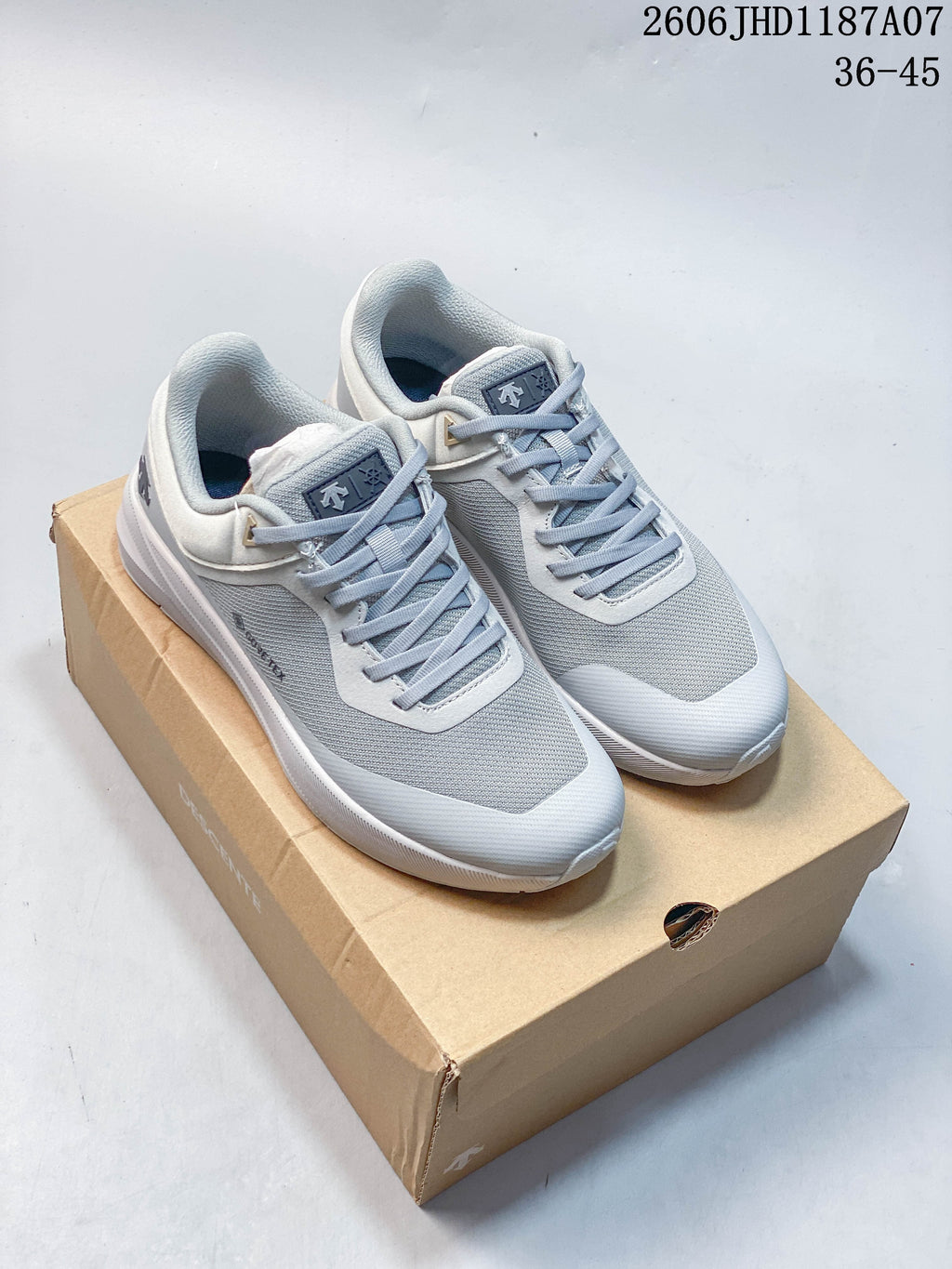 Pair of gray and white Descente Lavitate Trail Wire 3.0 sneakers on a shoebox.