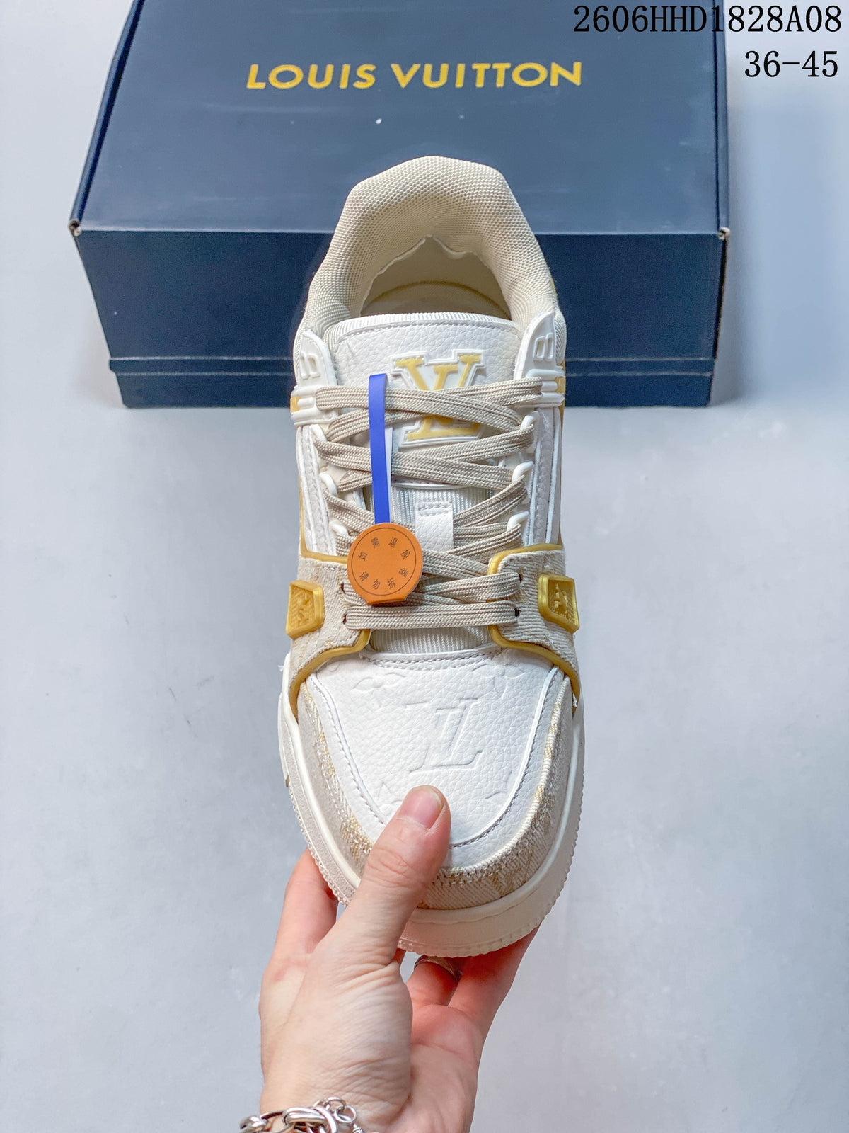 Top view of a lace-up sneaker with textured panels and gold-tone details.