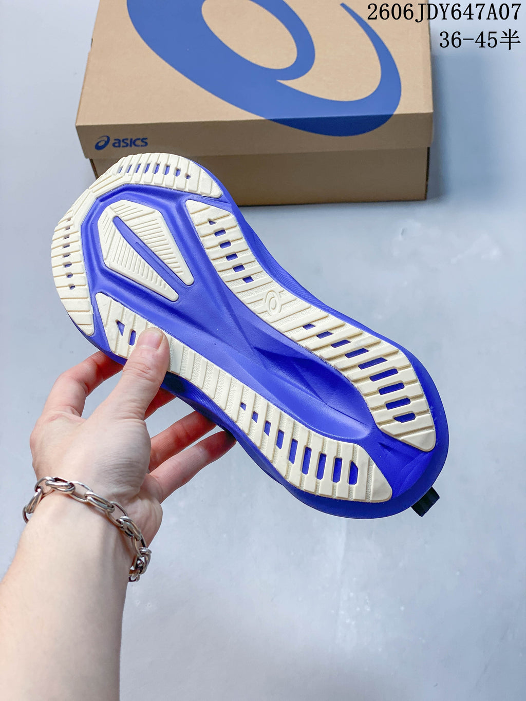 Underside of a running shoe showing a cream and purple outsole