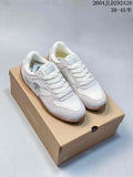White and pale gray Descente low-profile sneakers with gum-tone soles, shown on a branded shoebox.