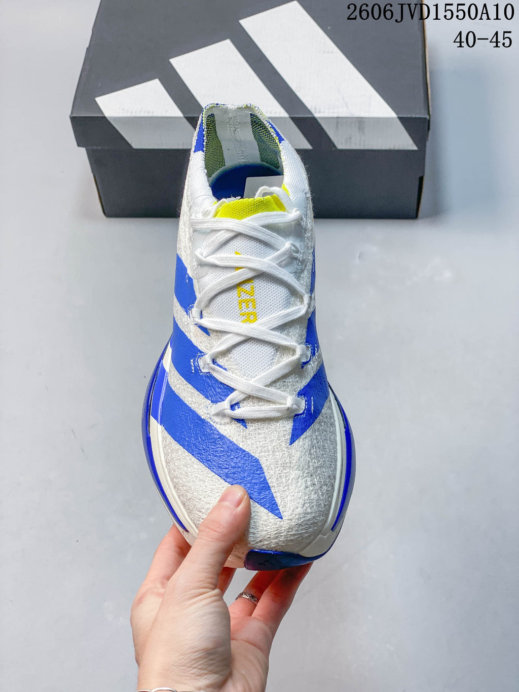 Top view of a white running shoe with blue stripes, white laces and a yellow tongue accent.