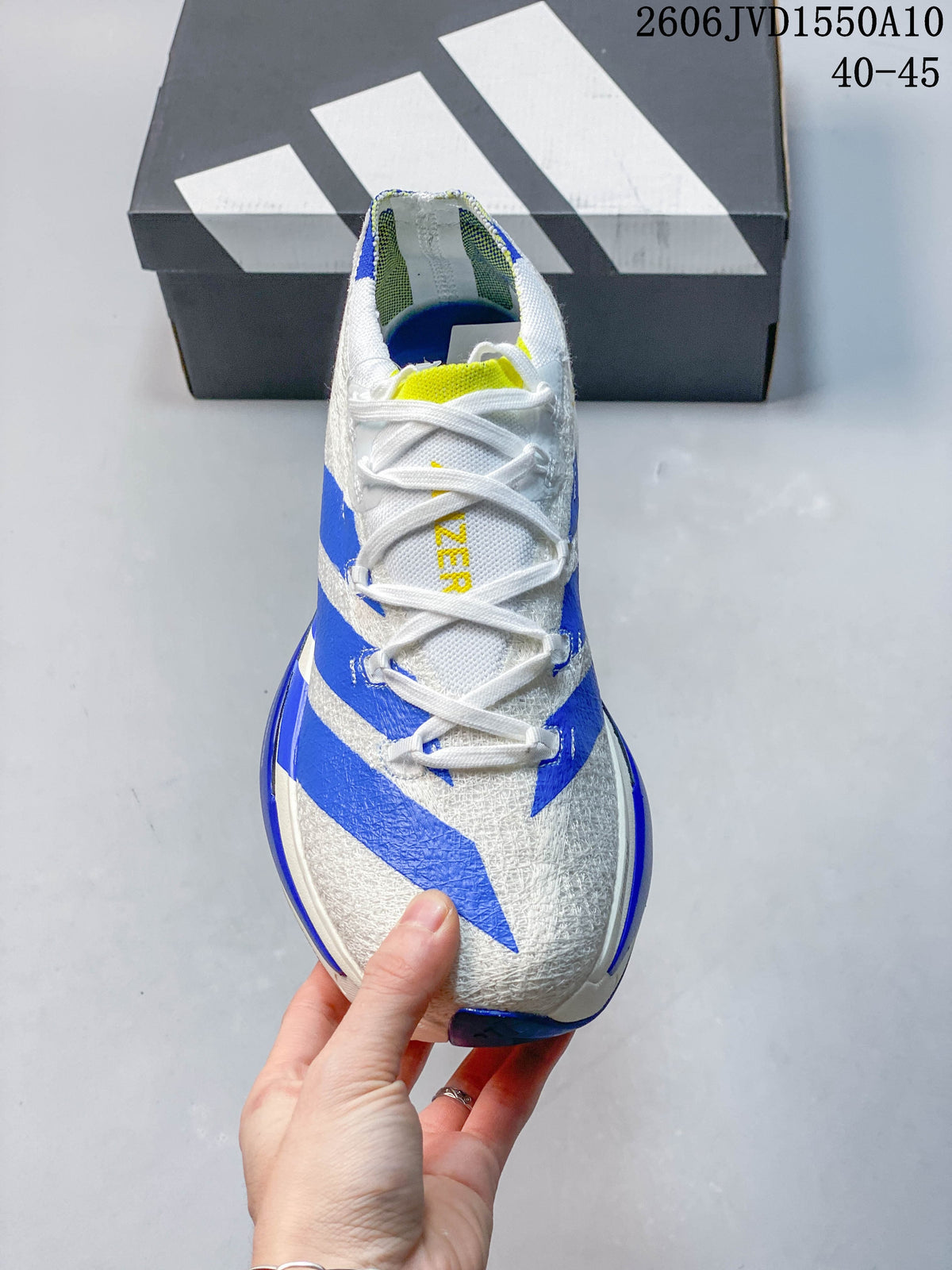 Top view of a white running shoe with blue stripes, white laces and a yellow tongue accent.