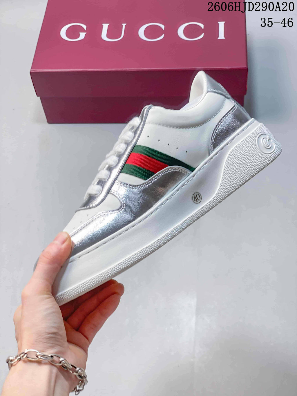 Side view of a white and silver low-top sneaker with green-and-red stripes