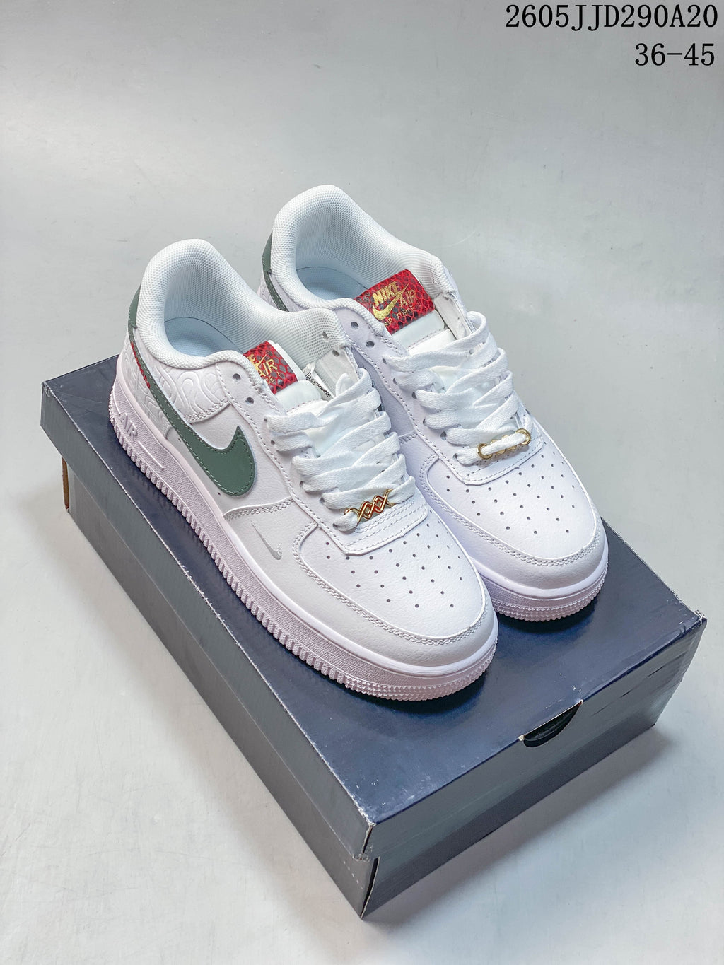 Pair of white Nike Air Force 1 Shadow sneakers with green side accents, red patterned tongue labels, and gold-tone lace hardware.
