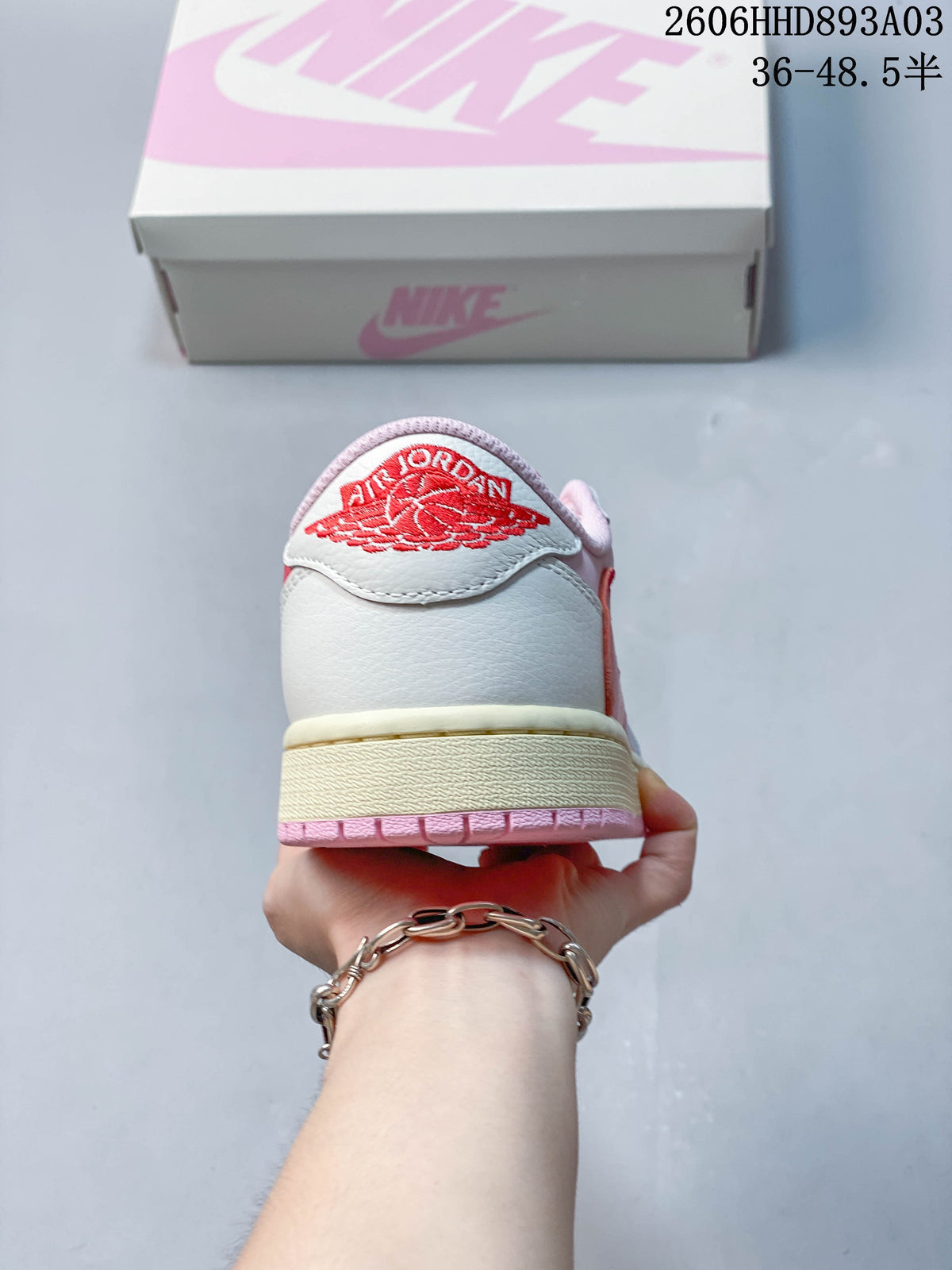 Rear view of a white and pink low-top sneaker with red Air Jordan Wings embroidery; image overlay states a size range.