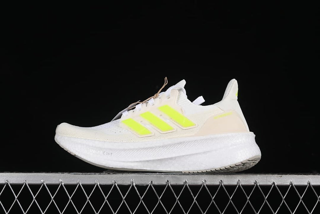 Side view of a white adidas Ultraboost 5 with bright lime accents