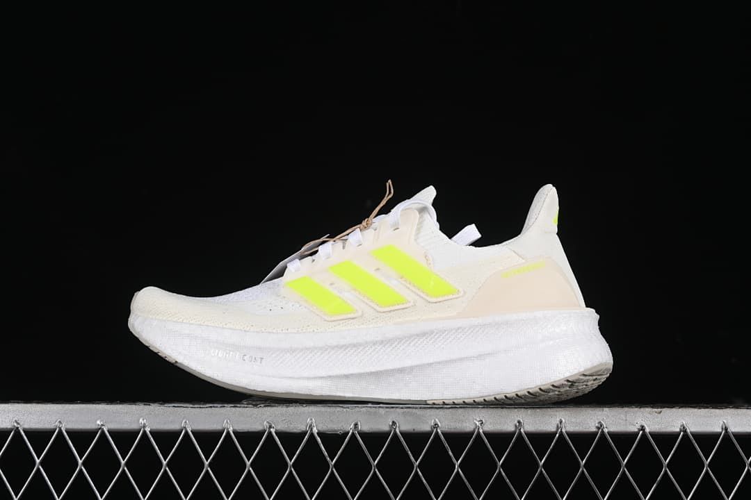 Side view of a white adidas Ultraboost 5 with bright lime accents