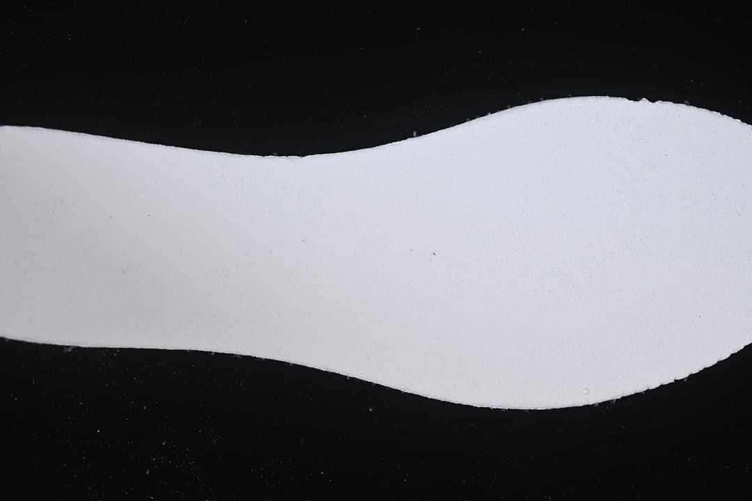 Plain light-colored shoe-shaped insert photographed against a black background