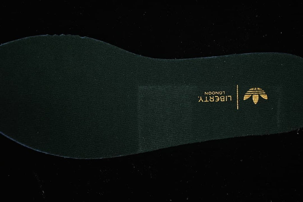 Close-up of the dark insole with gold trefoil branding.