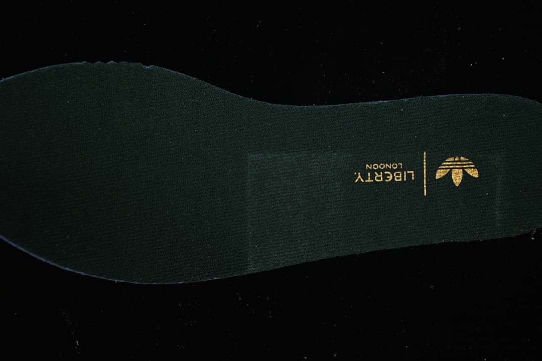 Close-up of the dark insole with gold trefoil branding.