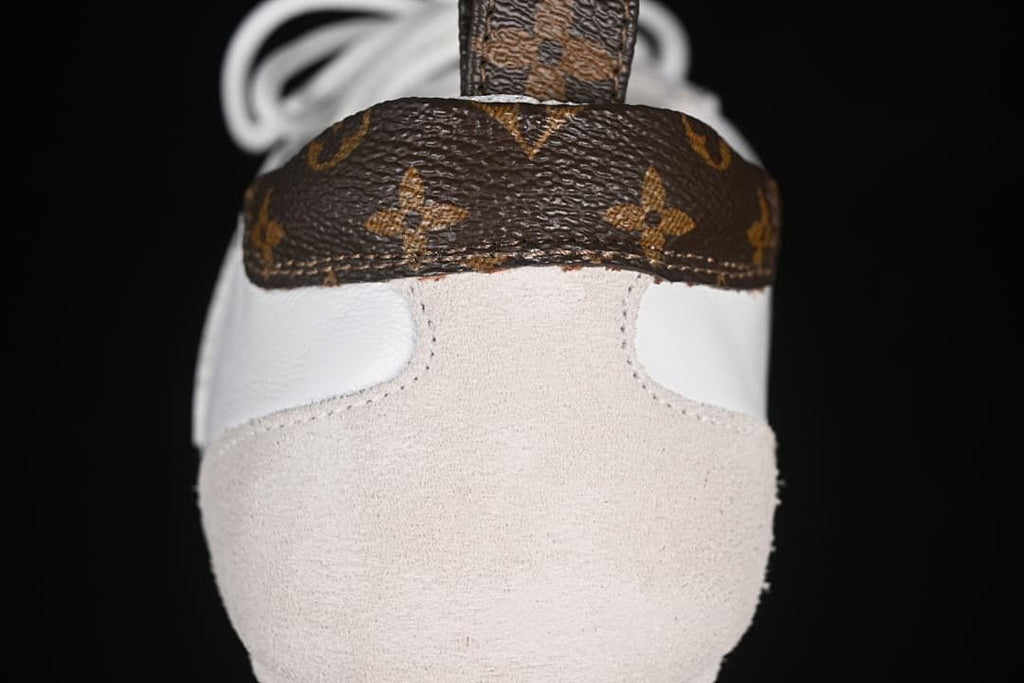 Heel detail showing a brown patterned panel, light beige overlay, and heel pull loop.