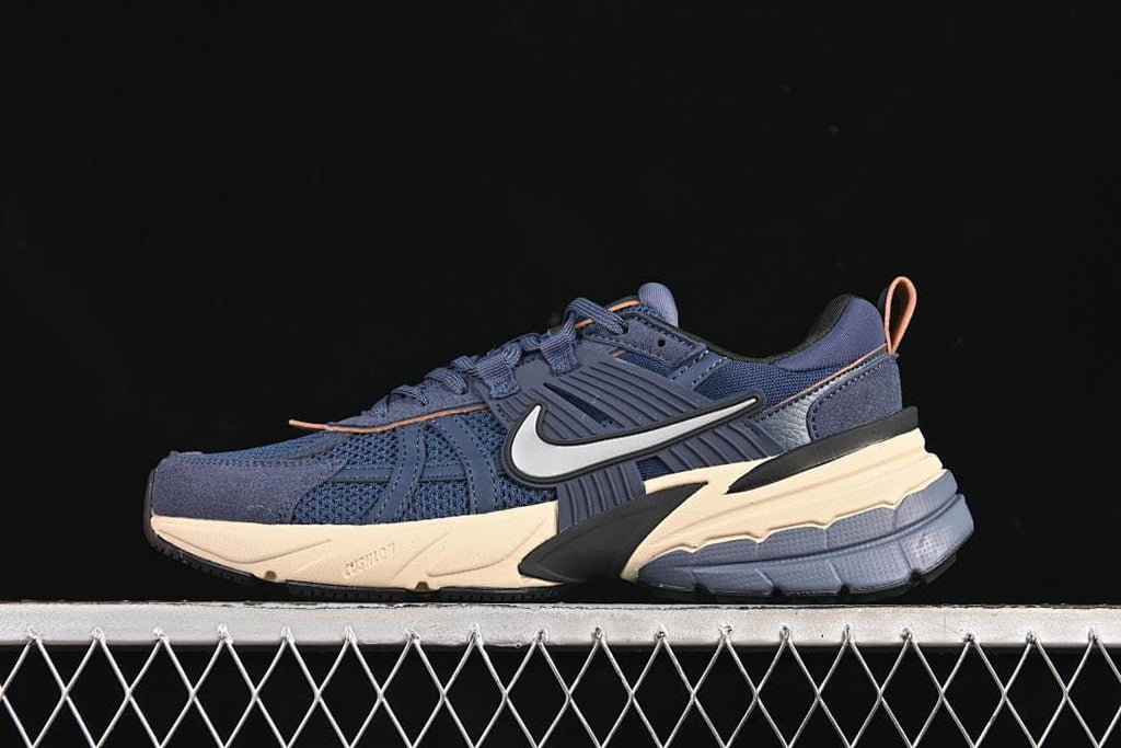 Side view of a navy Nike V2K Run sneaker with cream-toned sole accents