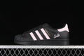 Side view of black Adidas Superstar sneakers with pink stripes and heel accents