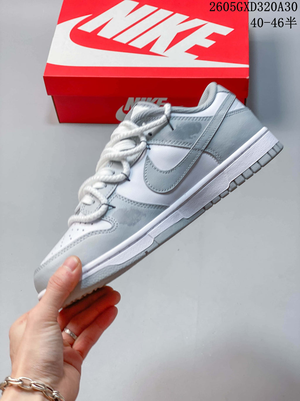 Side view of a white and gray low-top sneaker with a gray Swoosh and white midsole.