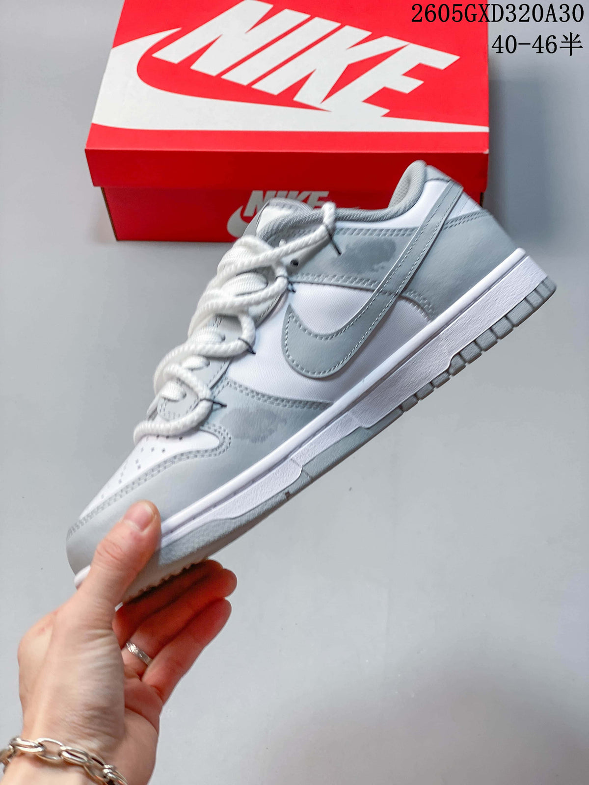 Side view of a white and gray low-top sneaker with a gray Swoosh and white midsole.
