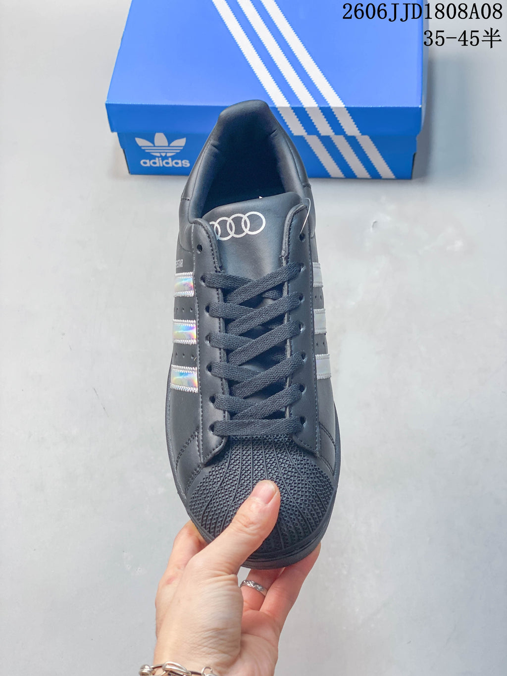 Front view of the charcoal Adidas Superstar with lace-up closure and textured shell toe.