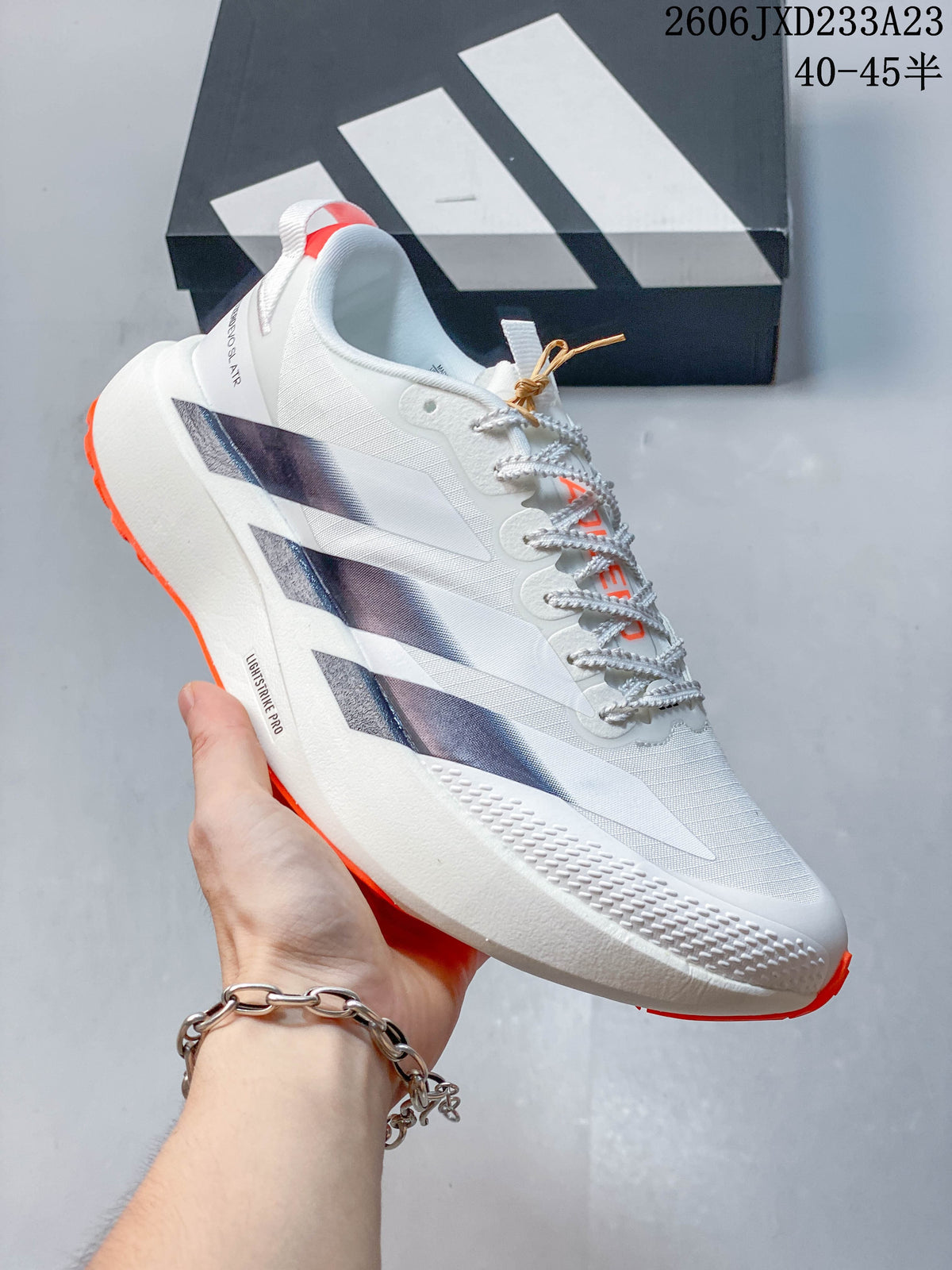 Angled side view of the white Adidas Adizero Evo SL ATR shoe with dark stripes and orange accents
