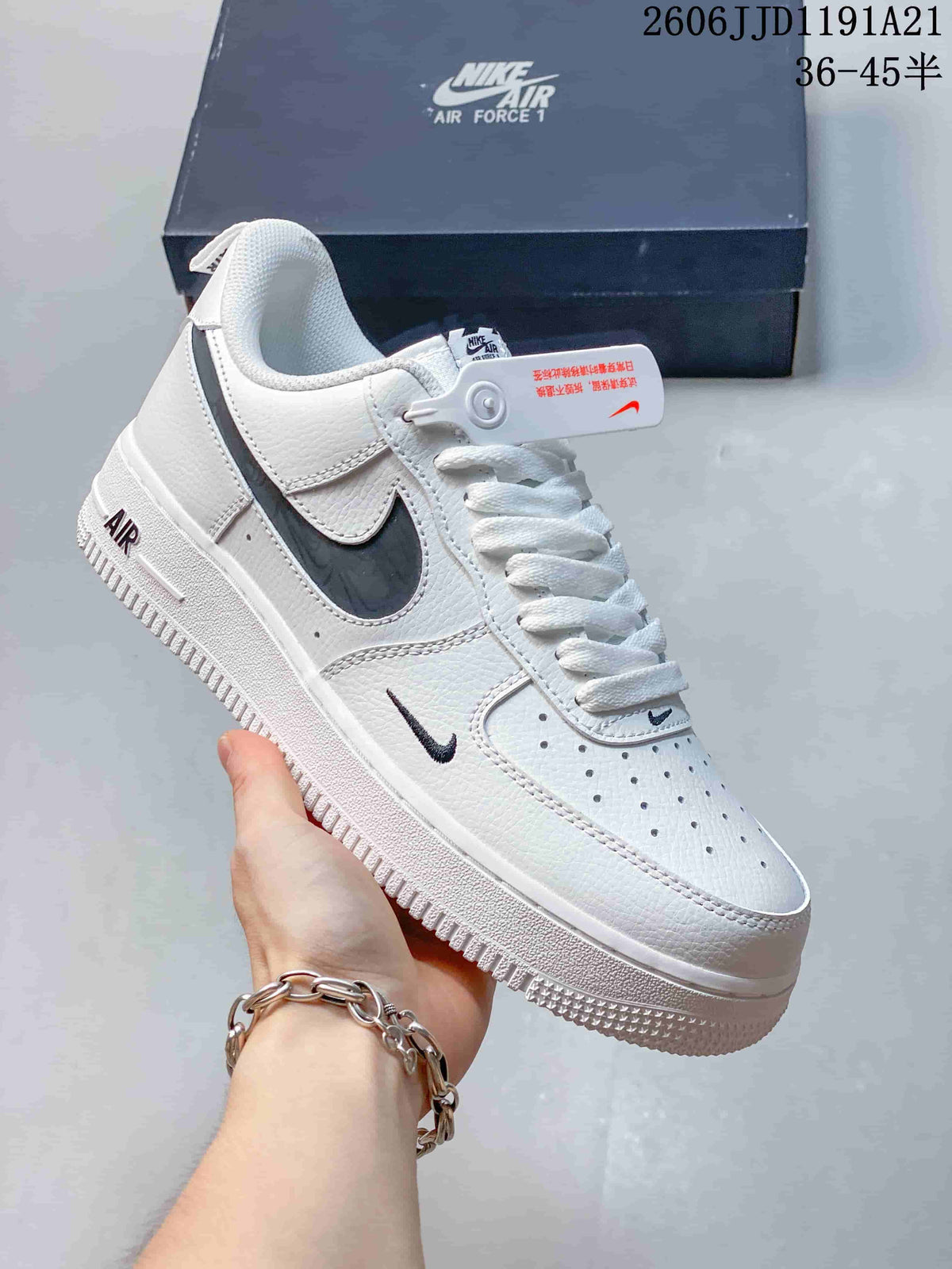 White low-top sneaker with dark side panel, small contrast Swoosh, and perforated toe.