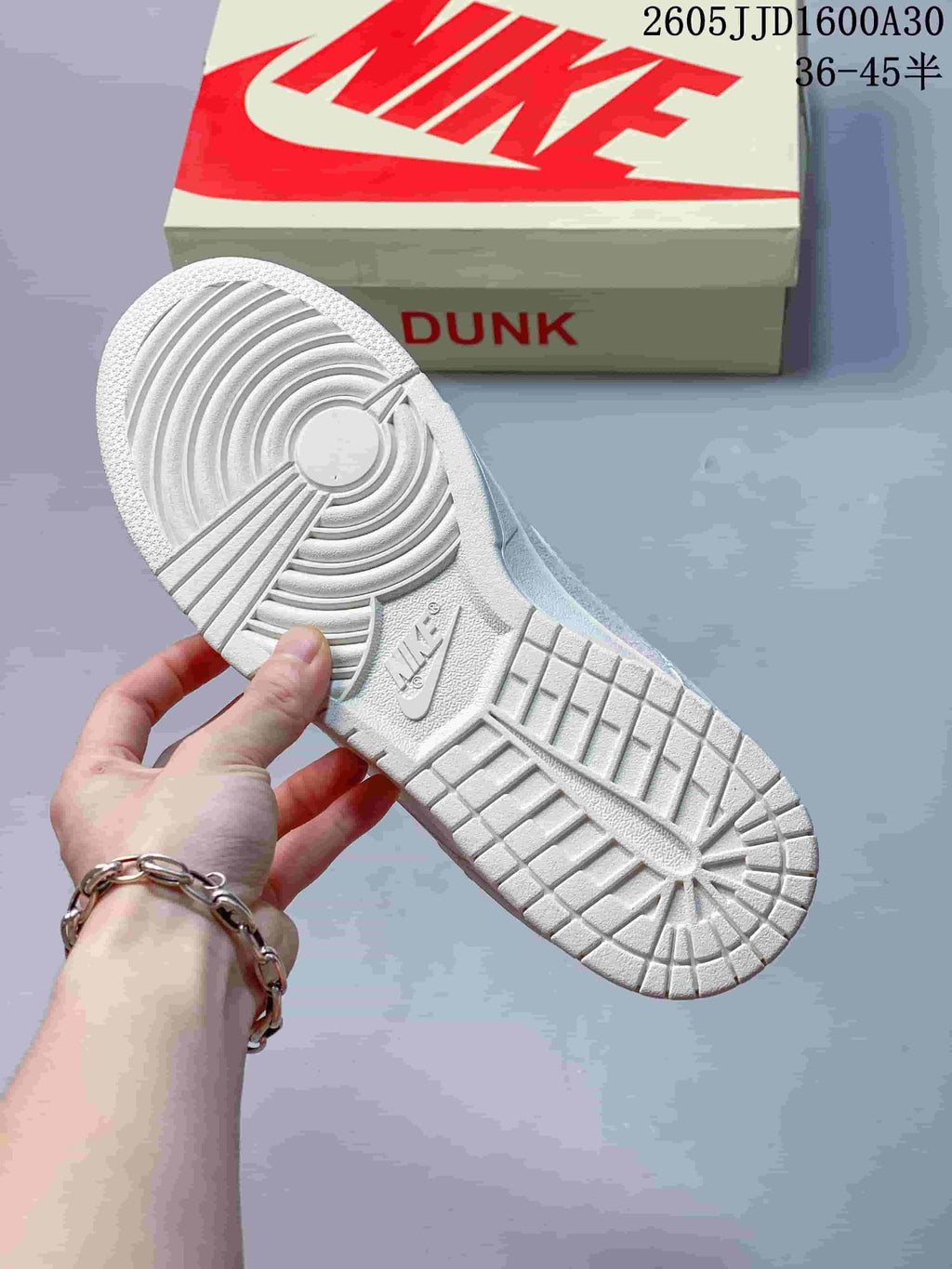 White outsole of a low-top sneaker with a Nike-marked shoebox in the background