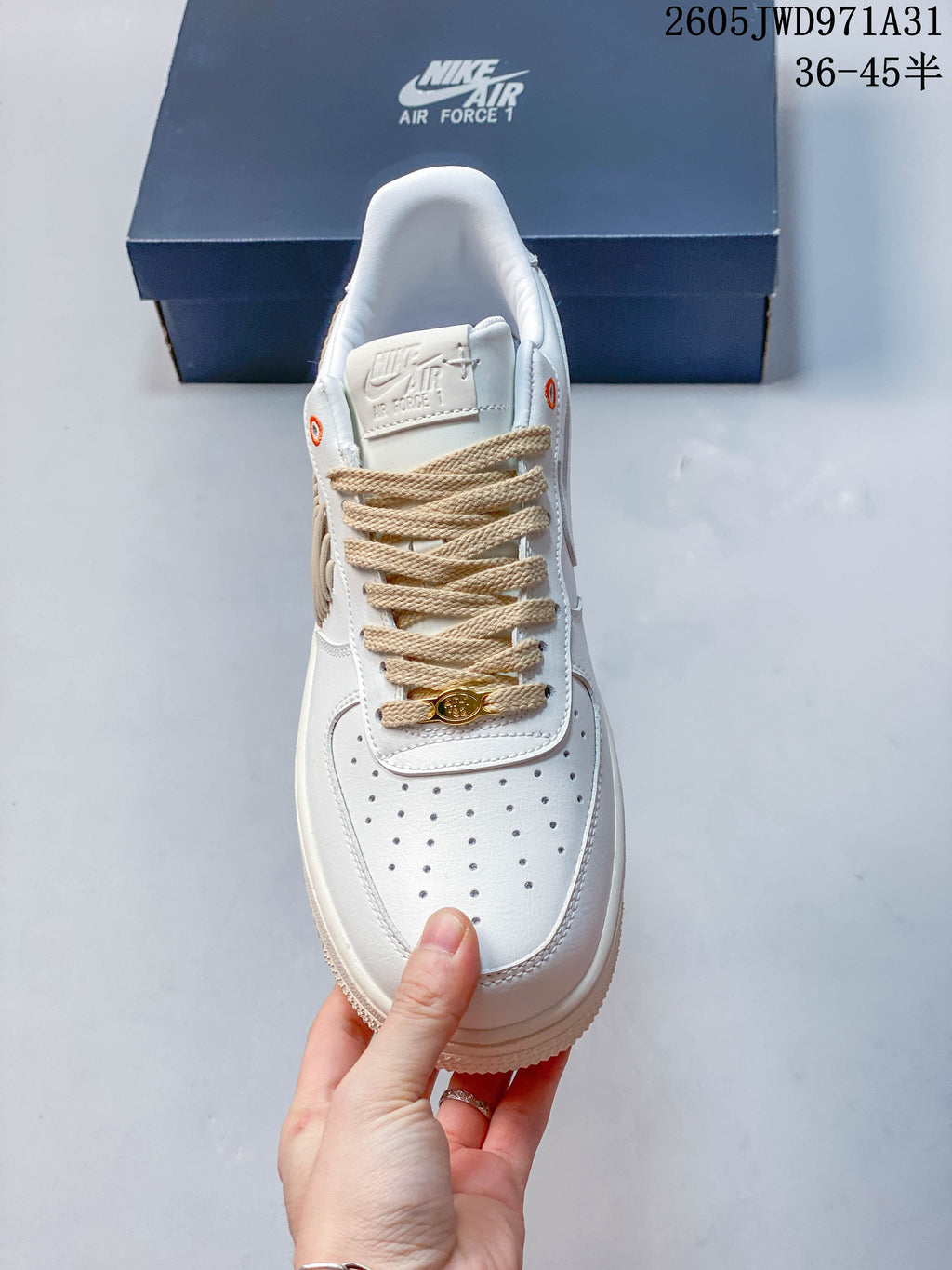 Top view of a white low-top sneaker showing its perforated toe, beige laces and lace ornament.