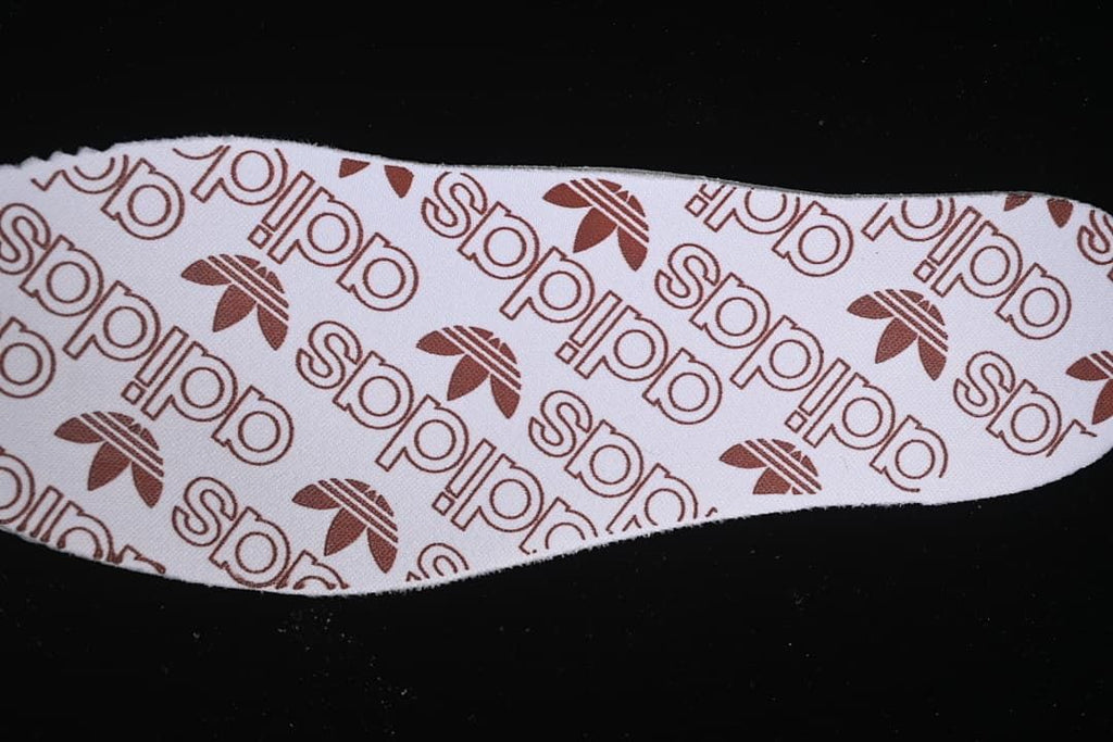Close-up of patterned sneaker insole with repeating adidas marks