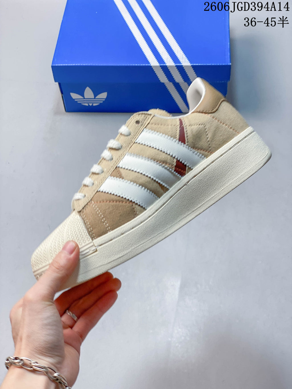 Side profile showing the three stripes, beige upper, and shell toe