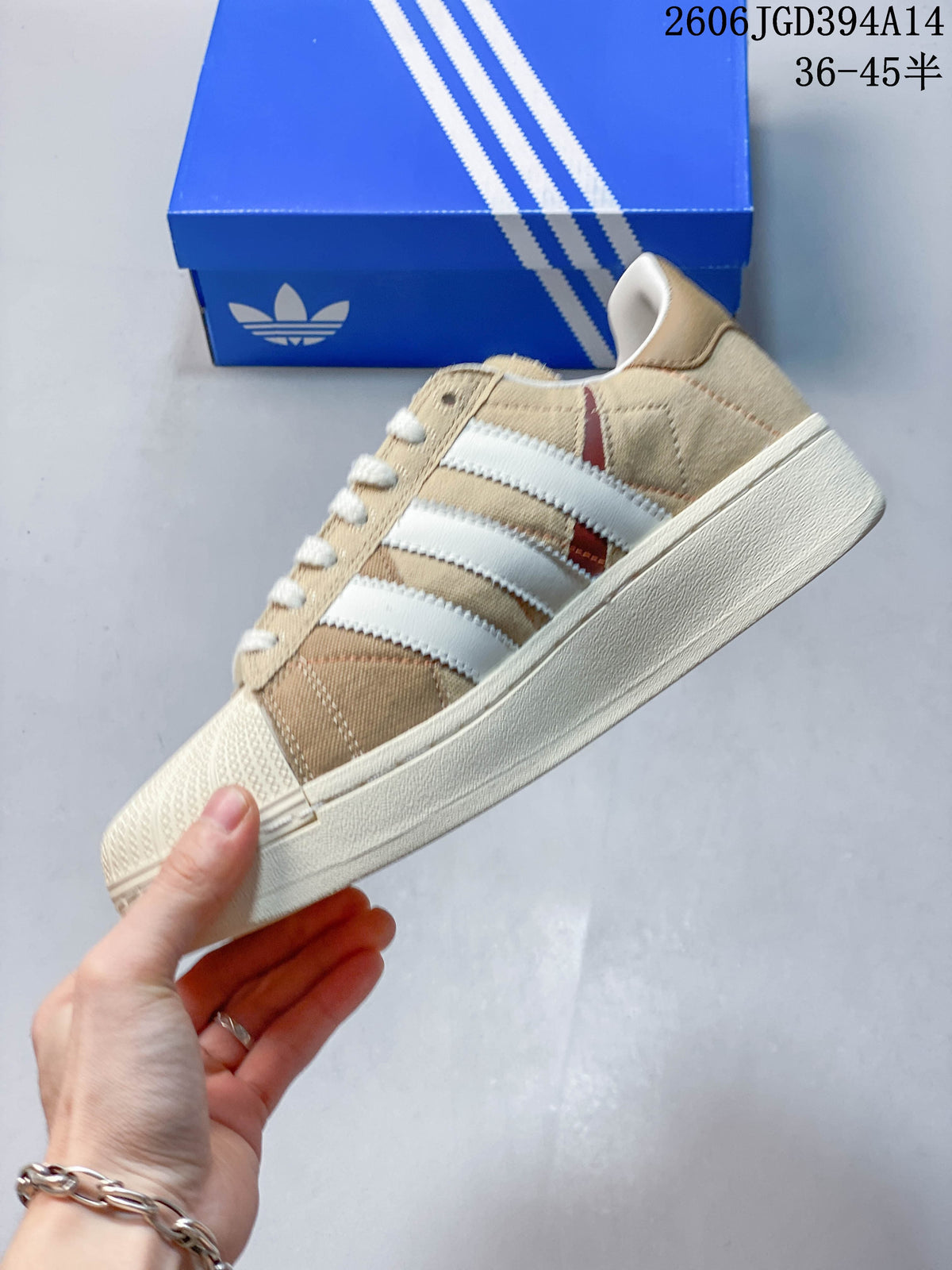 Side profile showing the three stripes, beige upper, and shell toe