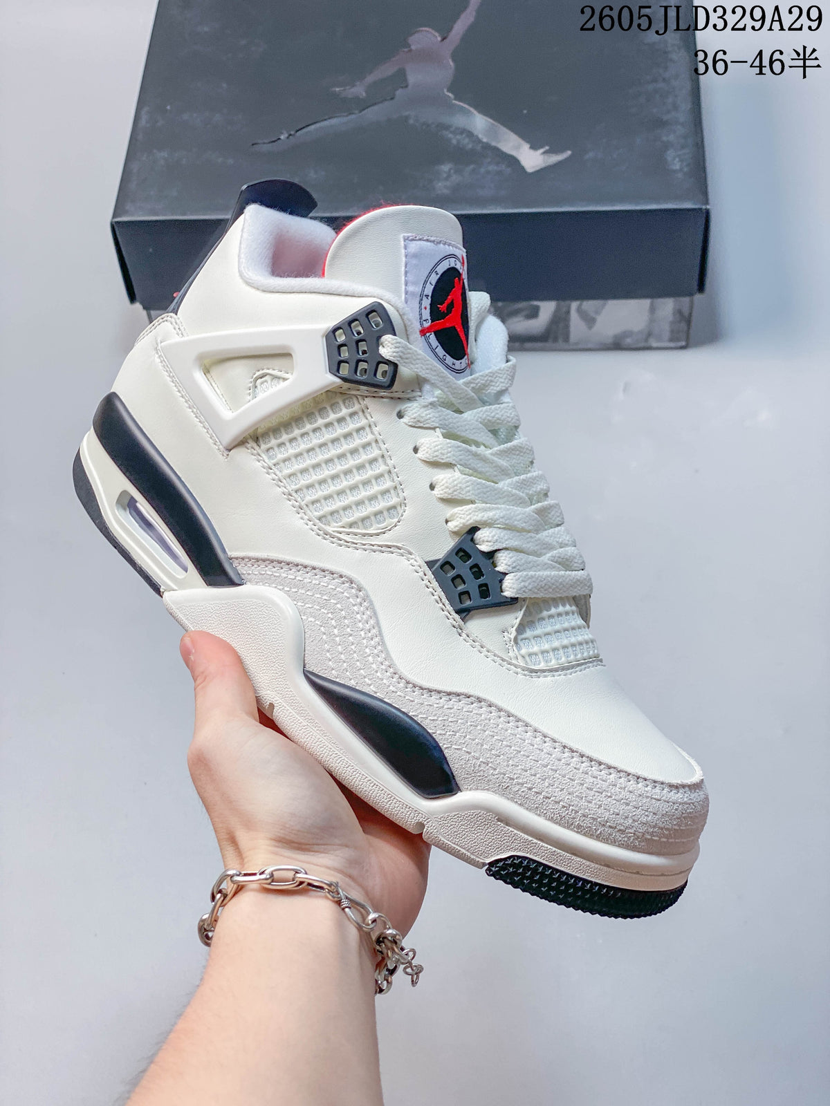 Side view of a white Jordan Air Jordan 4 Retro OG sneaker with dark accents and a visible heel cushioning window.