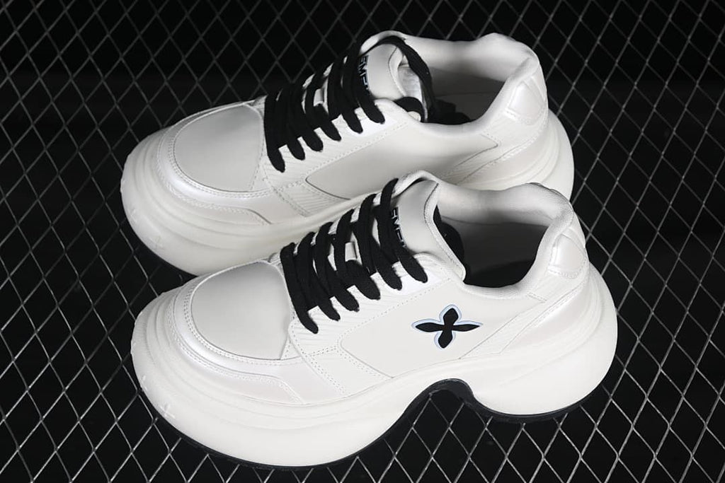 Pair of white low-top sneakers with black laces and thick sculpted soles