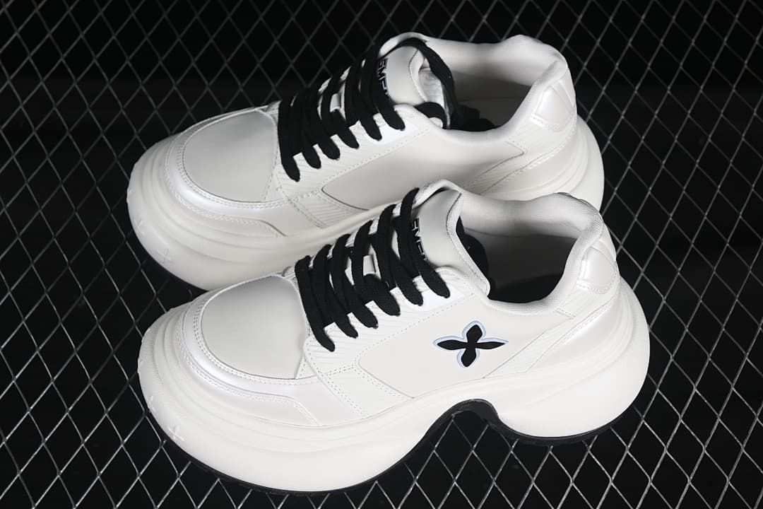Pair of white low-top sneakers with black laces and thick sculpted soles