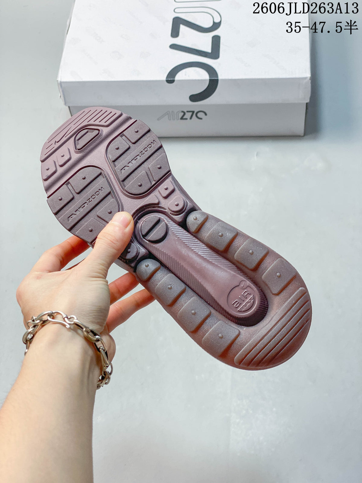 Underside of a dusty pink sneaker showing the patterned outsole and heel unit