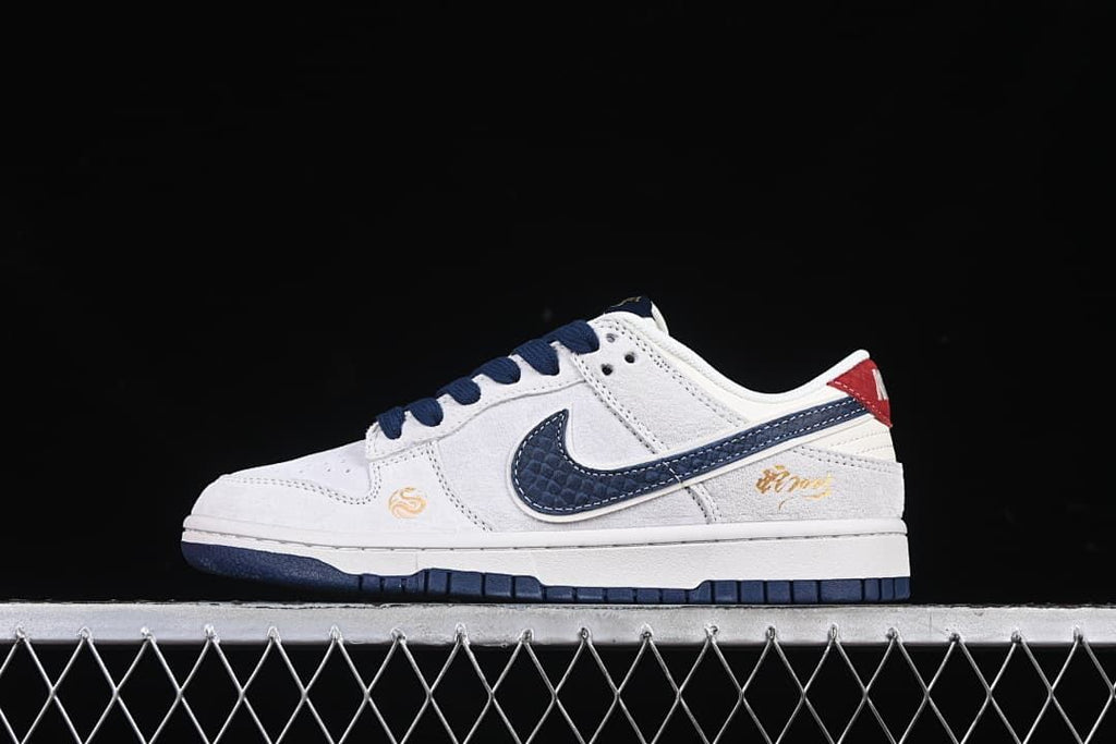 Side view of a white low-top Dunk sneaker with a navy snake-scale-pattern swoosh and red heel accent