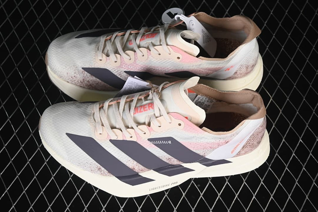 Pair of Adizero Adios Pro 4 shoes showing the off-white, pink, brown and dark colorway