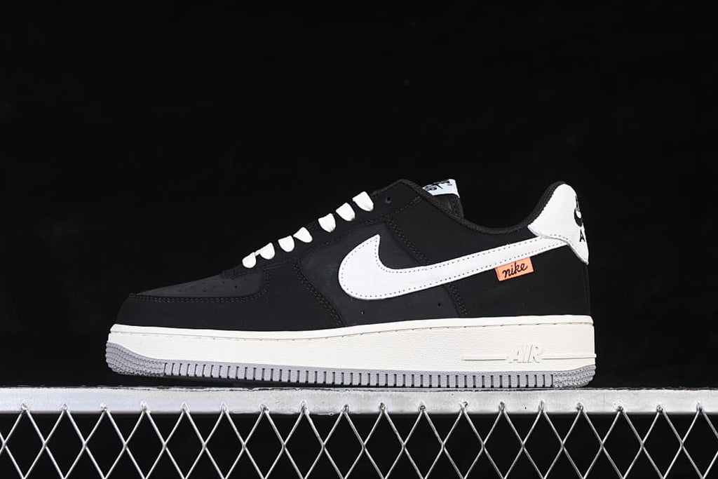 Opposite side view showing white Swoosh and orange accent tab on black Nike Air Force 1 '07 Low