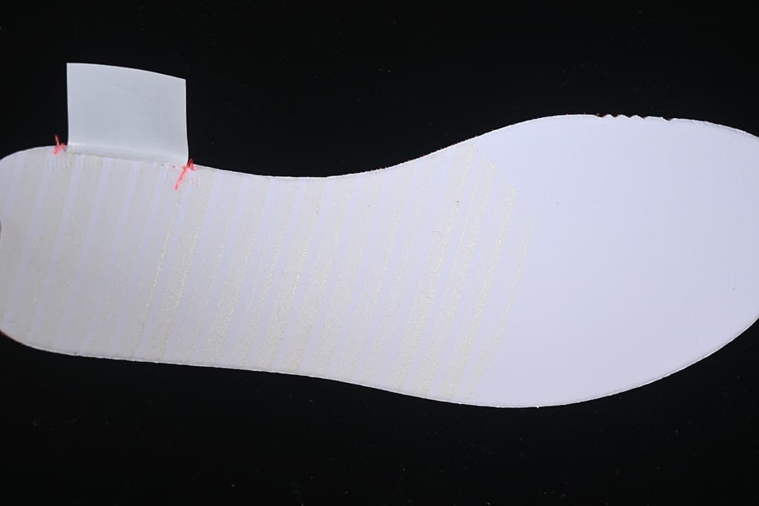 Close-up view of a white shoe insert against a dark background.