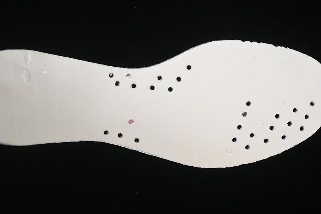 Underside view of the shoe's light-colored insole with perforations