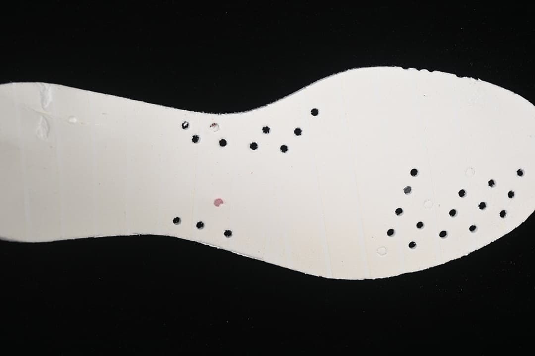 Underside view of the shoe's light-colored insole with perforations