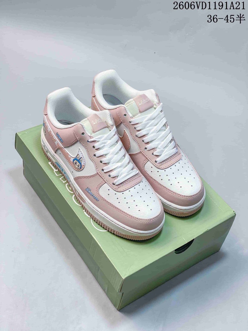 Pink and white low-top sneakers with Labubu-themed details displayed on a green box