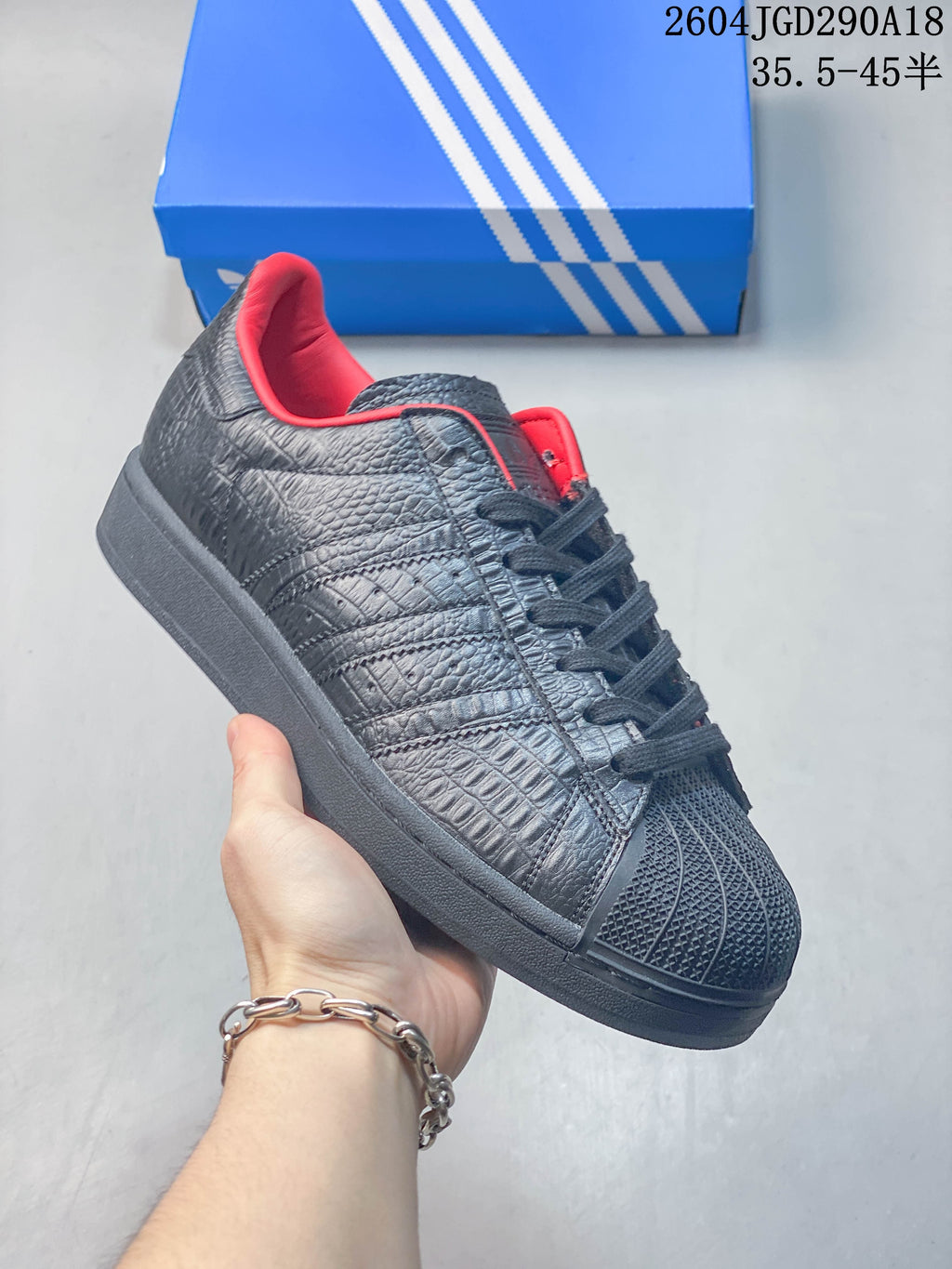 Angled side view of the black textured sneaker with shell toe and red lining.